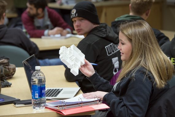 Student holding up a model of a floorplan