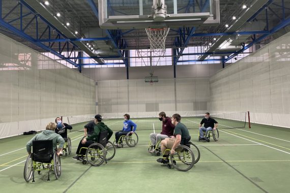 People in wheelchairs playing basketball in an indoor gym
