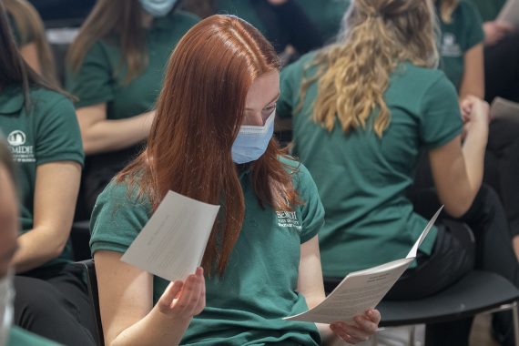 A BSU nursing student reading the nursing induction ceremony program