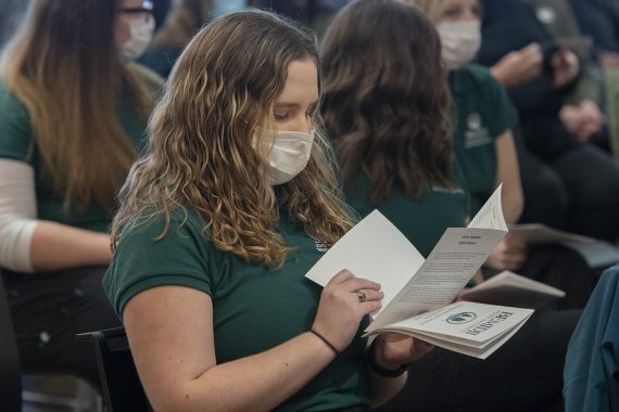 A BSU nursing student reading the nursing induction ceremony program