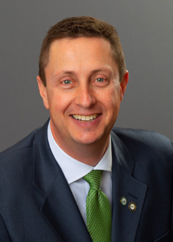 A portrait of BSU president John Hoffman. He is wearing a dark blue suit and a light green tie.