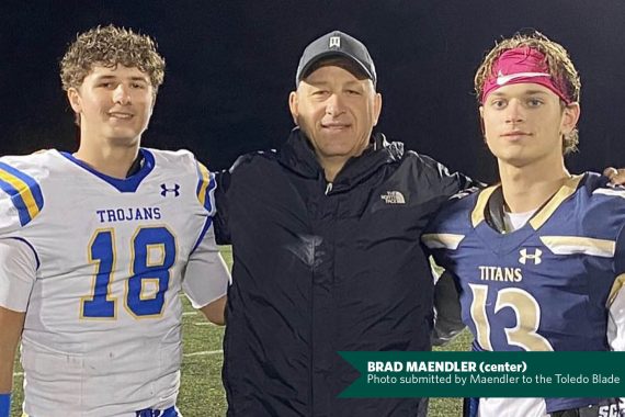 former BSU quarterback Brad Maendler stands between two players wearing football uniforms.