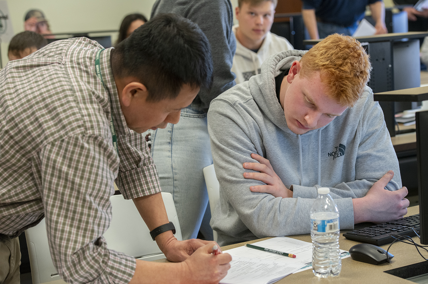 A professor leaning over to show a student something on a piece of paper