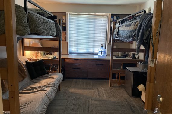 Tamarack double room looking in from the hallway. Each bed is lofted. One has a futon underneath and the other a mini refrigerator and storage container.