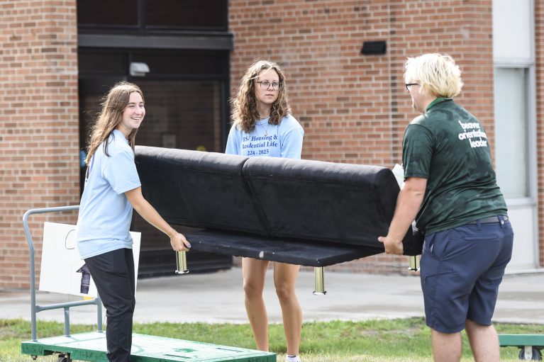 Housing & Orientation staff help load a futon onto a cart during BSU move-in day.